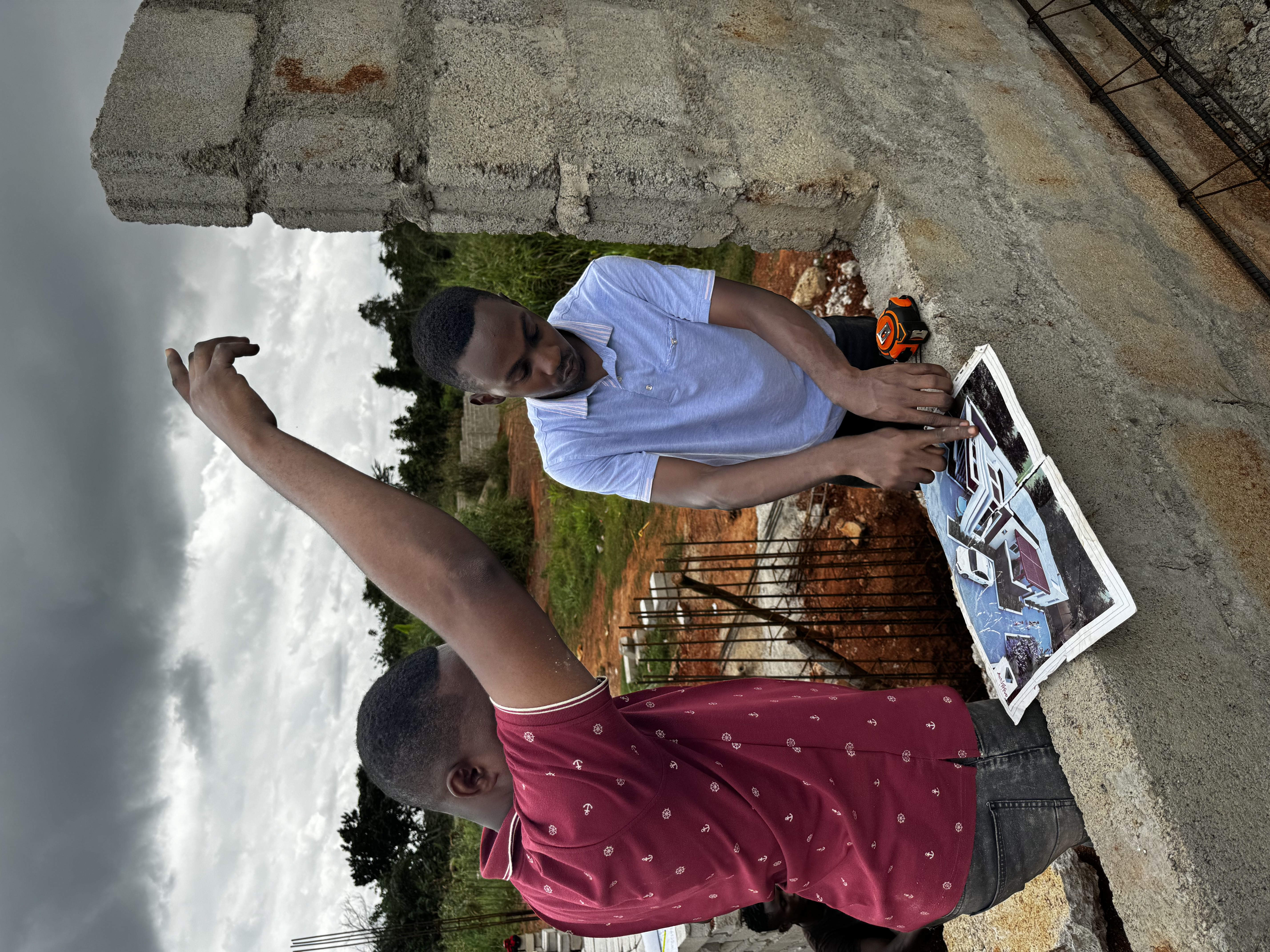 Site leads reviewing a house plan on a Ghana project